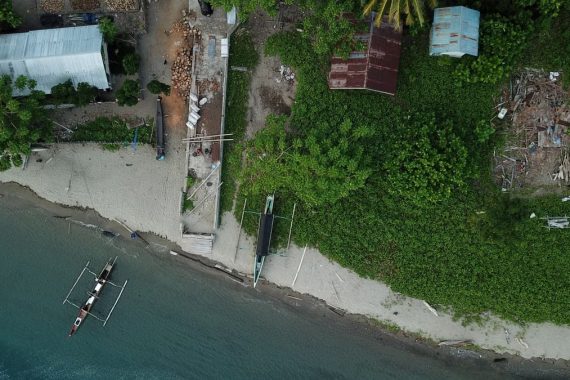 Drone shot capturing a coastal scene with boats and greenery in Una-Una, Indonesia.